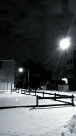 Illuminated street light on snow covered field at night