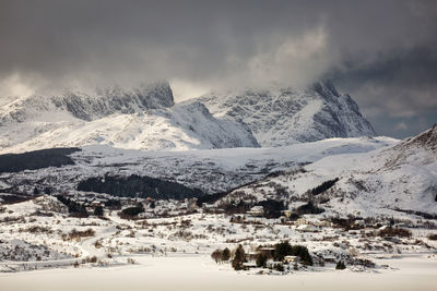 Scenic view of townscape by snowcapped mountains against sky