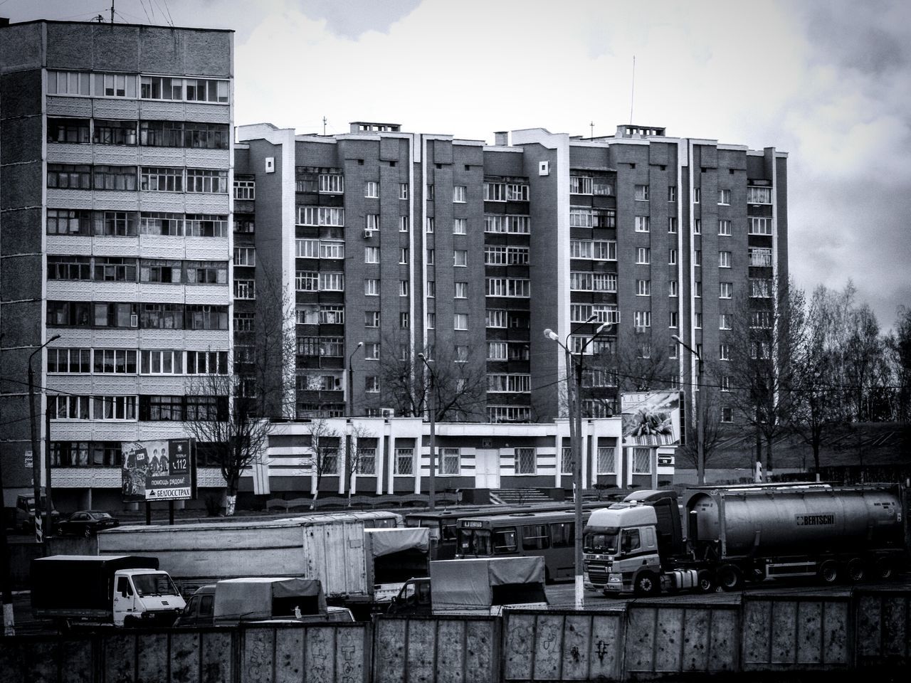 building exterior, architecture, built structure, city, sky, building, transportation, residential building, window, mode of transport, residential structure, day, car, outdoors, land vehicle, no people, low angle view, street, city life, cloud - sky