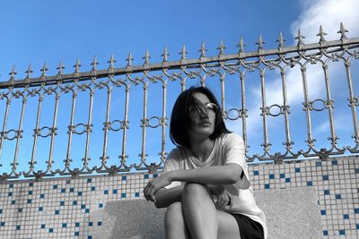 Low angle view of woman sitting against sky