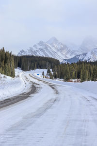 Road amidst snowcapped mountains against sky