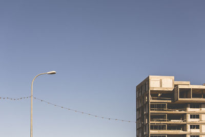 Low angle view of bird perching on street light against sky