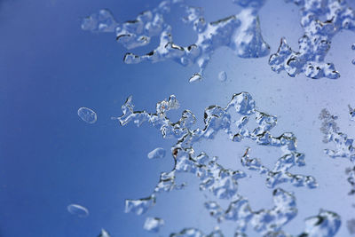 Close-up of wet glass against blue sky