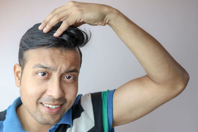 Close-up portrait of smiling young man against gray background