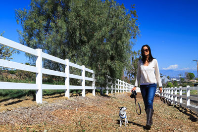 Portrait of young woman with dog walking against trees