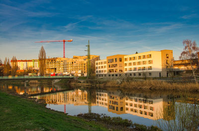 Buildings by river against sky in city