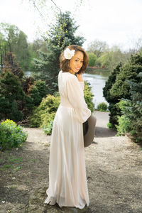 Portrait of happy woman standing against trees