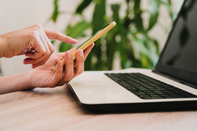 Midsection of woman using mobile phone on table