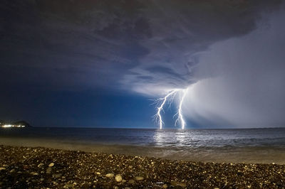 Lightning over sea against sky at night