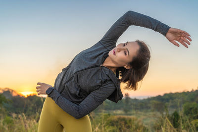 Attractive young woman stretching her arms and legs before her early morning exercise at local park