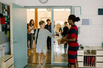 Student giving phone to female professor while walking in classroom