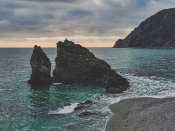 Rock formation on sea against sky during sunset