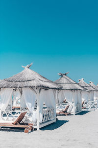 Traditional windmill on beach against clear blue sky