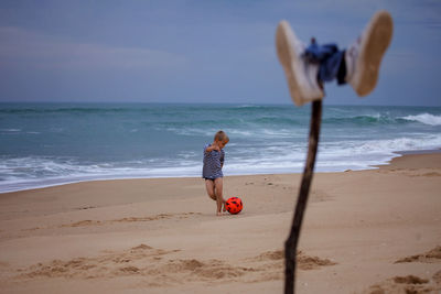 A small football fan barefoot repeats the tricks of his idol right on the ocean. football everywhere