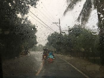 Road seen through wet window in rainy season