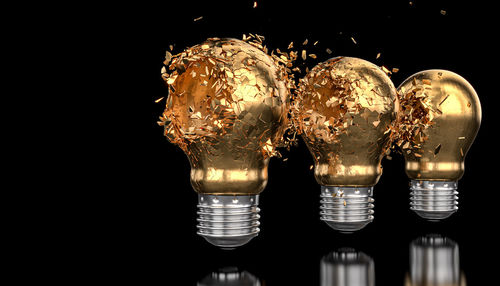 Close-up of illuminated light bulb against black background