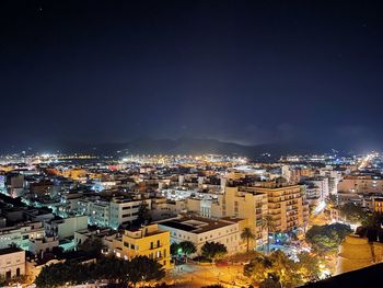 High angle view of illuminated buildings against sky at night