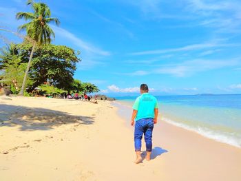 Rear view of men on beach against sky