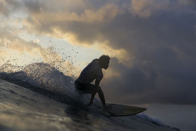 Surfer on a wave at sunset time