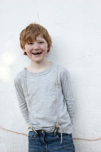 Portrait of smiling boy standing against wall