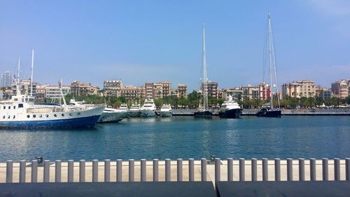 Sailboats moored in harbor against sky