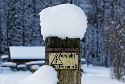 Close-up of snow covered sign against trees