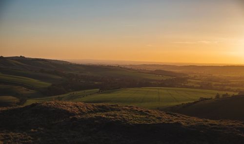 Scenic view of agricultural field against sky during sunset