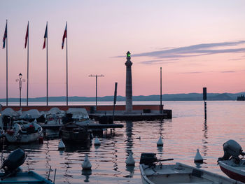 Sailboats moored in sea against sky during sunset