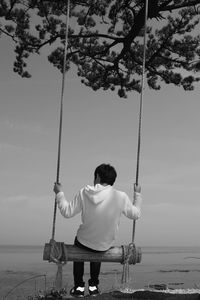 Rear view of man swinging at beach