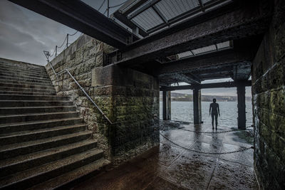 Rear view of man standing on staircase of building