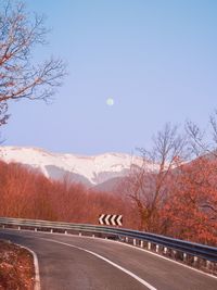 Road by trees against sky