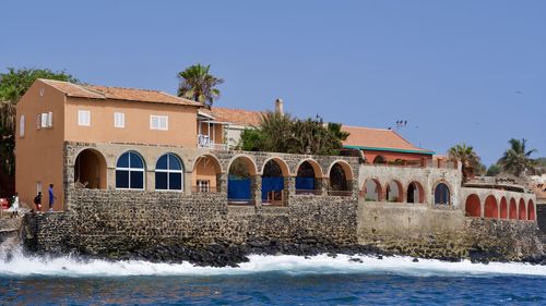 Building by river against clear blue sky