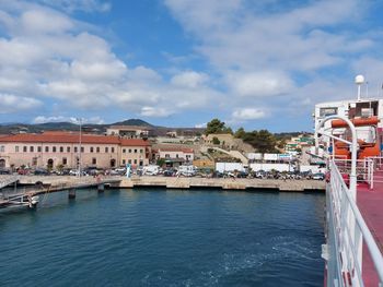 View of buildings by sea against cloudy sky