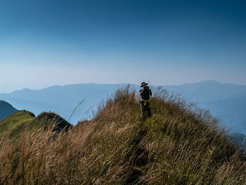 Rear view of man standing on mountain against sky