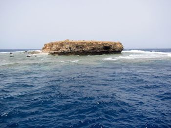 Scenic view of rocks in sea against clear sky