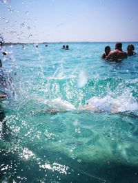 People swimming in sea against sky