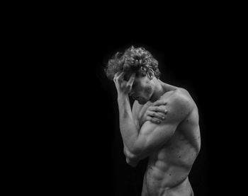 Shirtless man against black background