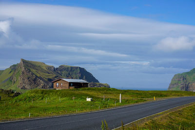 Road by buildings against sky