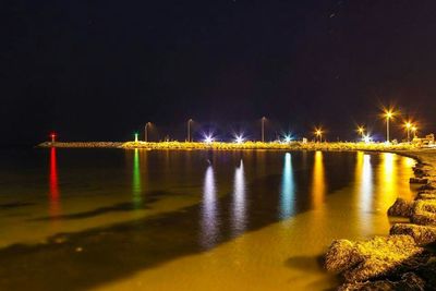Illuminated bridge over river at night