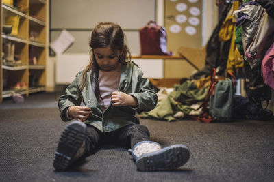 Girl wearing jacket sitting on carpet at day care center