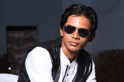 Portrait of young man wearing sunglasses sitting at home