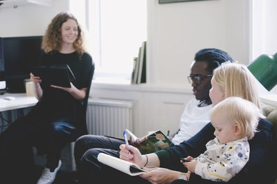 Working mother with baby discussing with colleagues in creative office