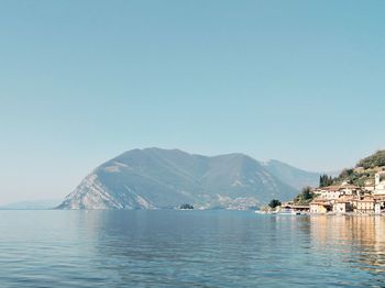 Scenic view of sea and mountains against clear blue sky