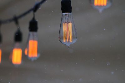 Close-up of illuminated light bulb hanging over water