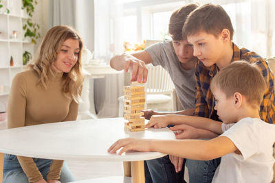 Family , in home enthusiastically play a board game made of wooden rectangular blocks