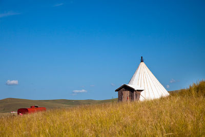 Traditional windmill on field against clear blue sky