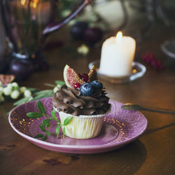 Tea light candles and cupcake in plate on table