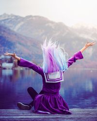 Low angle view of woman dancing on mountain against sky