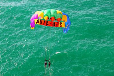 High angle view of people paragliding over sea