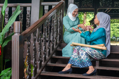 Rear view of people sitting on railing